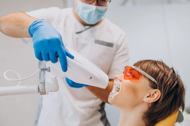 woman whitening teeth dentistry with special equipment 768x512